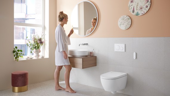 Жінка у ванній кімнаті з унітазом-біде Geberit AquaClean Alba Жінка у ванній кімнаті з унітазом-біде Geberit AquaClean Alba